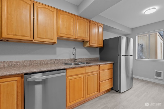 kitchen featuring stainless steel appliances, sink, and light hardwood / wood-style floors