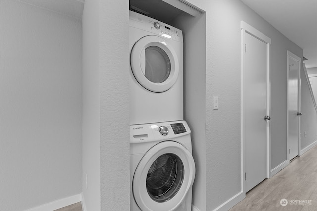 laundry area featuring stacked washer / dryer and light hardwood / wood-style floors