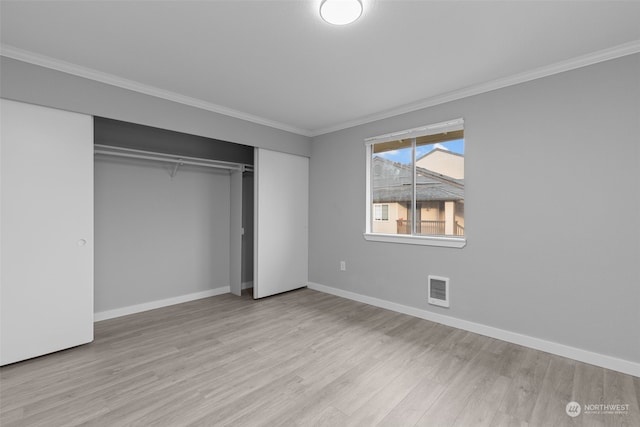 unfurnished bedroom featuring ornamental molding, a closet, and light wood-type flooring