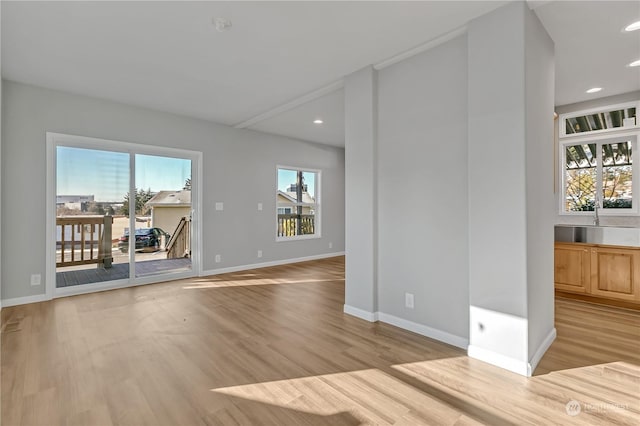 unfurnished living room with a healthy amount of sunlight, sink, and light hardwood / wood-style flooring