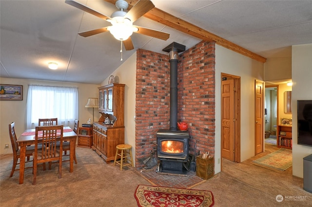 carpeted dining room with lofted ceiling with beams, ceiling fan, and a wood stove