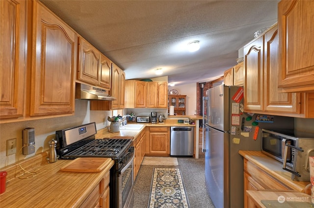 kitchen with wooden counters, appliances with stainless steel finishes, sink, and a textured ceiling