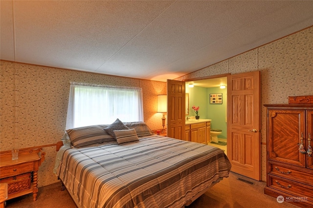 carpeted bedroom featuring ensuite bath, vaulted ceiling, and a textured ceiling