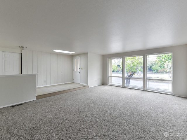 unfurnished living room featuring a skylight and carpet