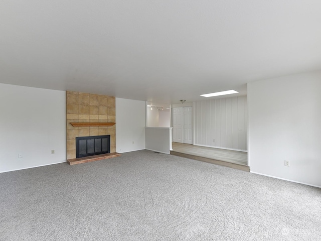 unfurnished living room with a tiled fireplace and carpet flooring