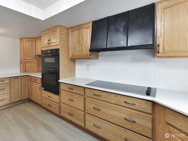 kitchen featuring tasteful backsplash, light wood-type flooring, and black appliances