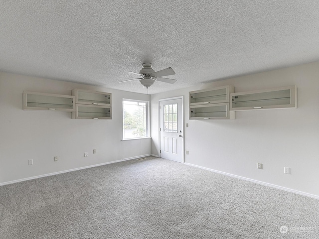 empty room featuring a textured ceiling, carpet floors, and ceiling fan