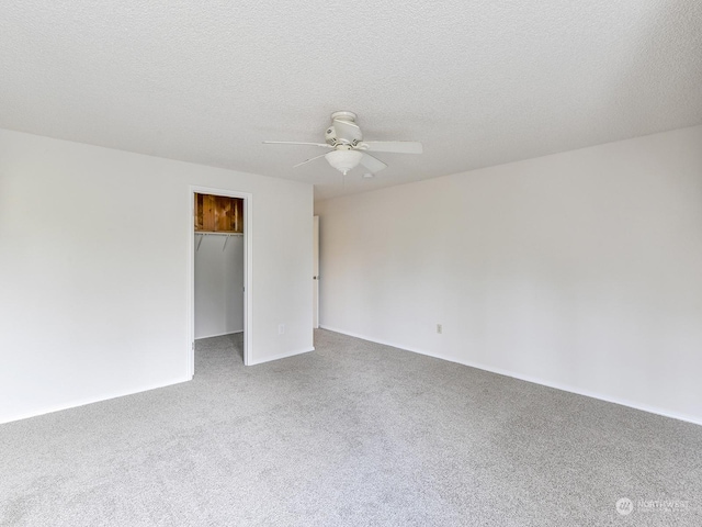 carpeted spare room featuring a textured ceiling and ceiling fan