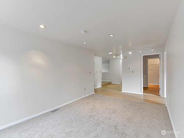 unfurnished room with rail lighting and light carpet