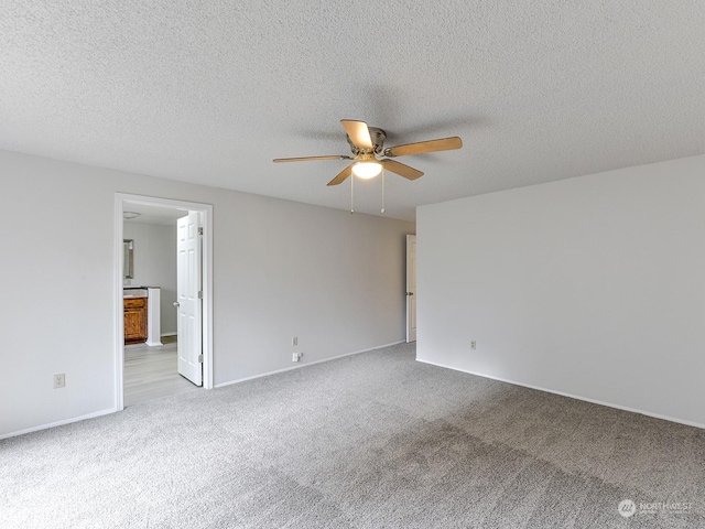 spare room featuring ceiling fan, light colored carpet, and a textured ceiling