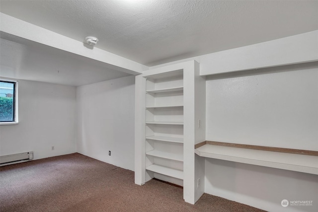 basement with a baseboard heating unit, a textured ceiling, and carpet