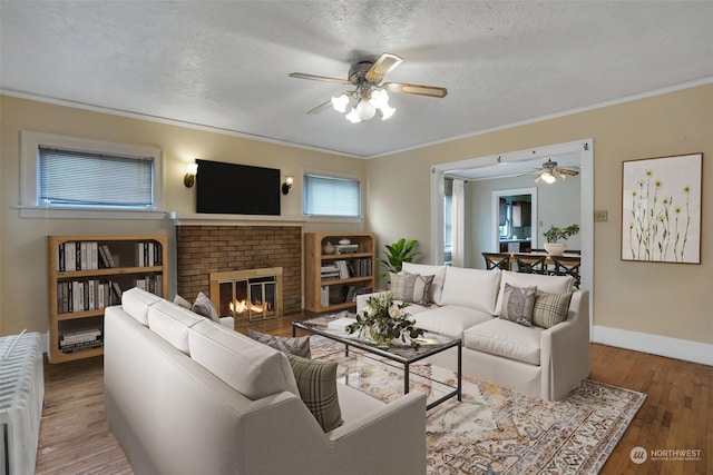 living room featuring wood-type flooring, ornamental molding, a fireplace, and a textured ceiling