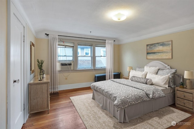 bedroom featuring cooling unit, radiator heating unit, crown molding, and wood-type flooring