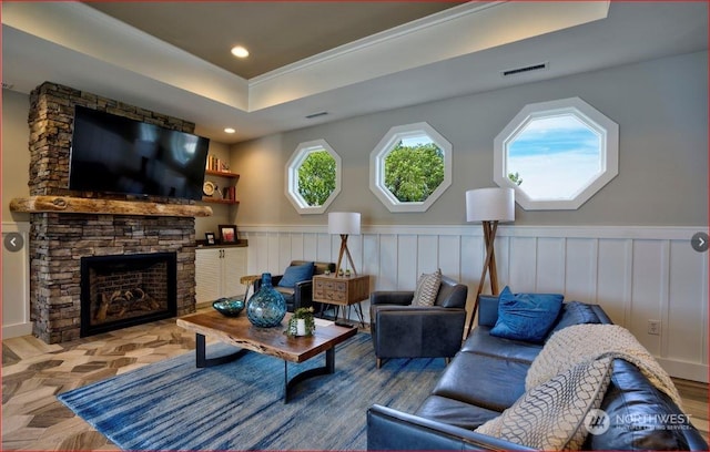 living room featuring a tray ceiling and a fireplace