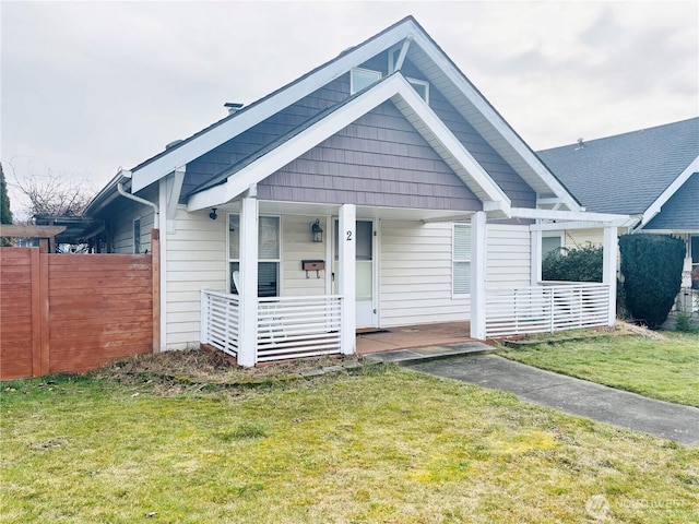 view of front of home featuring covered porch, a front yard, and fence