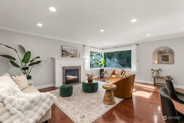 living room featuring a tiled fireplace, wood-type flooring, and ornamental molding