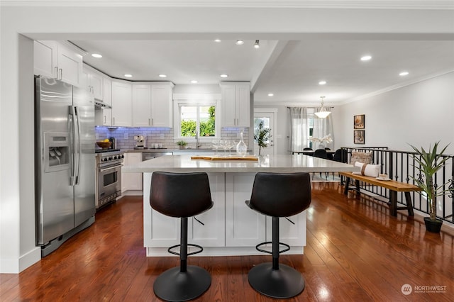 kitchen with white cabinetry, dark hardwood / wood-style flooring, a kitchen island, and appliances with stainless steel finishes