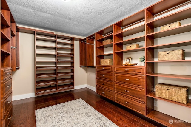 spacious closet featuring built in desk and dark hardwood / wood-style floors