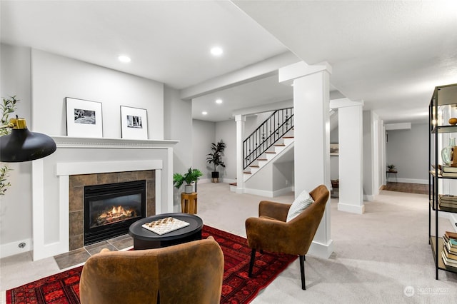 carpeted living room with a tile fireplace and ornate columns