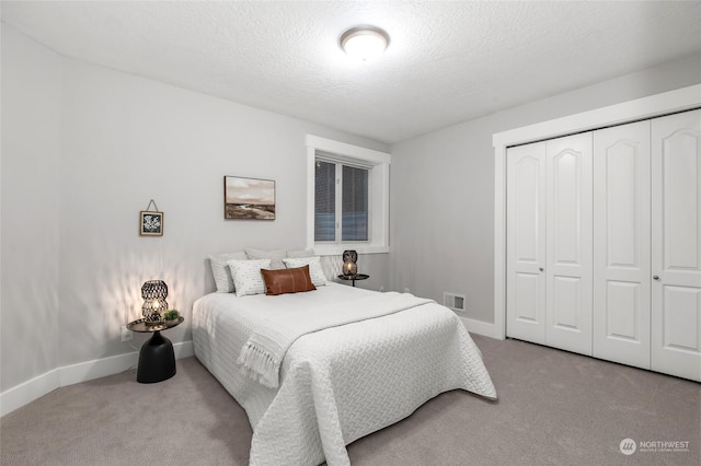 carpeted bedroom featuring a closet and a textured ceiling