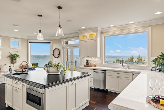 kitchen featuring stainless steel appliances, white cabinetry, a water view, and sink