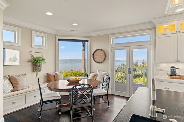 dining space featuring ornamental molding, dark hardwood / wood-style floors, and a water view