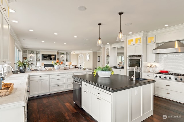 kitchen with sink, wall chimney exhaust hood, white cabinets, and appliances with stainless steel finishes