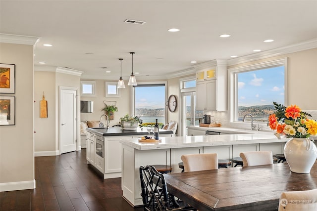 kitchen with pendant lighting, white cabinetry, dark hardwood / wood-style flooring, and crown molding