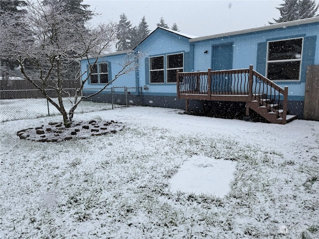 snow covered rear of property with a deck