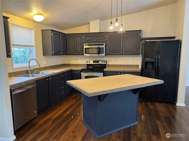 kitchen featuring sink, appliances with stainless steel finishes, a kitchen island, decorative light fixtures, and vaulted ceiling