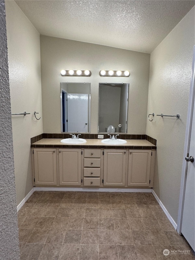 bathroom with lofted ceiling, vanity, and a textured ceiling