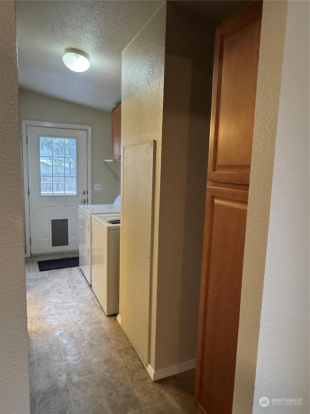 laundry area featuring cabinets, separate washer and dryer, and a textured ceiling