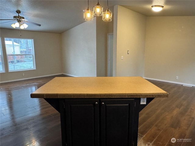 kitchen with dark hardwood / wood-style flooring, decorative light fixtures, a center island, and a breakfast bar area