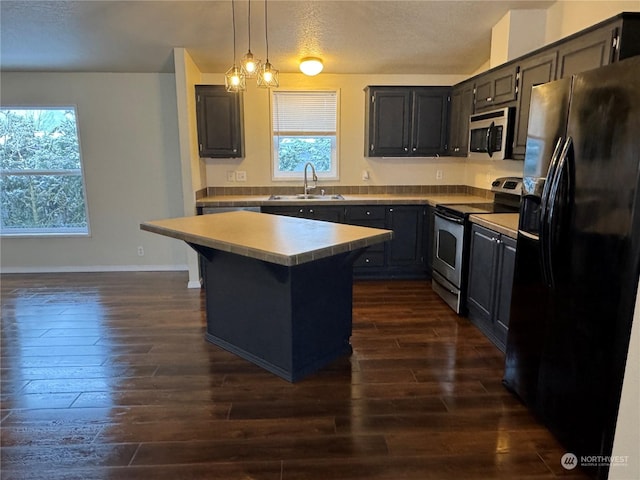 kitchen featuring a kitchen island, sink, hanging light fixtures, stainless steel appliances, and plenty of natural light