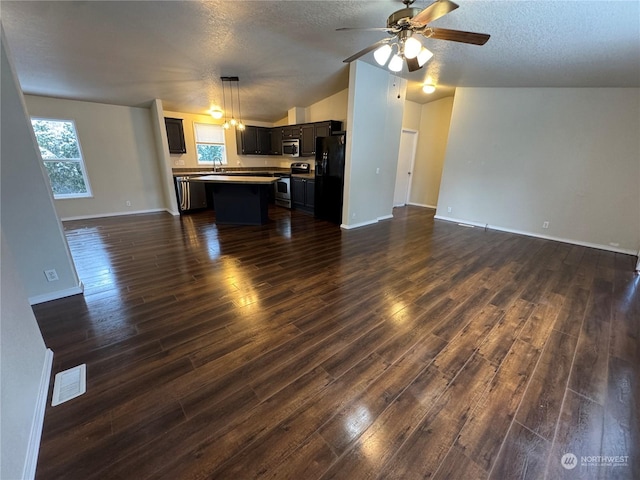 unfurnished living room with dark wood-type flooring, ceiling fan, vaulted ceiling, and a textured ceiling