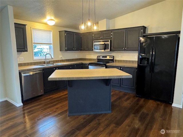 kitchen featuring dark wood-type flooring, sink, a center island, a textured ceiling, and stainless steel appliances