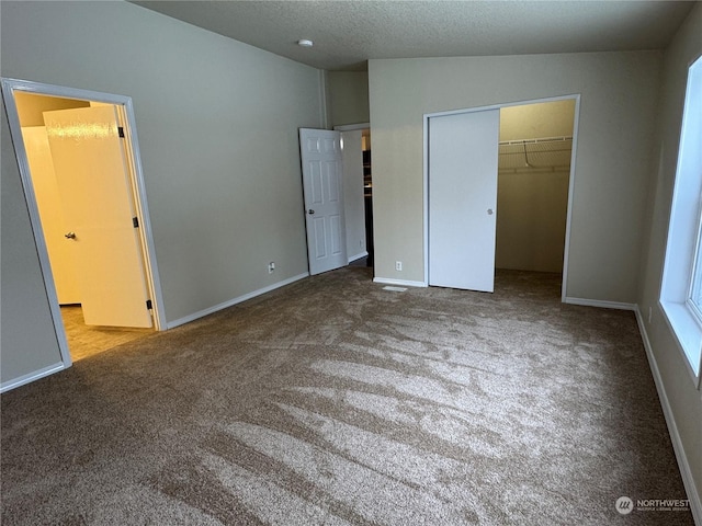 unfurnished bedroom featuring ensuite bath, light carpet, a textured ceiling, and a closet