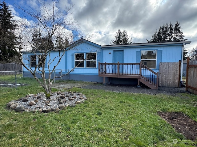 back of property featuring a wooden deck and a lawn