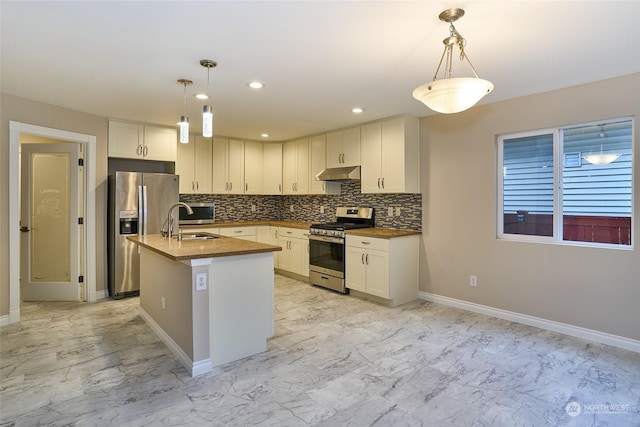 kitchen with pendant lighting, appliances with stainless steel finishes, sink, and a center island with sink