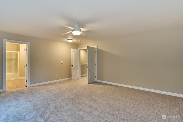 unfurnished bedroom with ceiling fan, light colored carpet, and ensuite bath