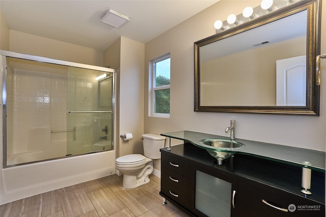 full bathroom with vanity, shower / bath combination with glass door, and toilet