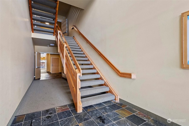 stairway featuring a towering ceiling and carpet flooring