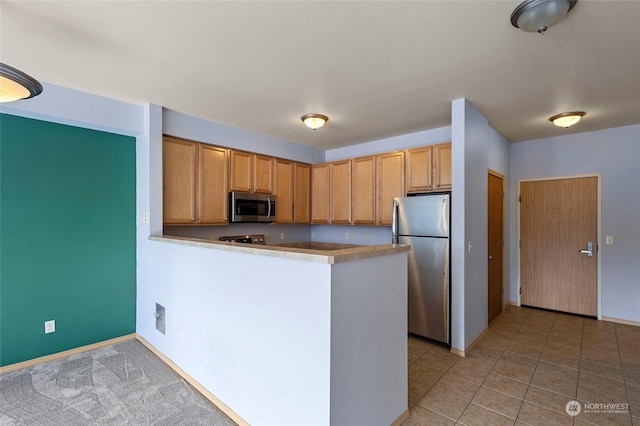 kitchen with stainless steel appliances, kitchen peninsula, and light tile patterned flooring