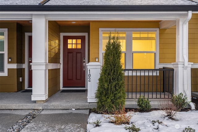 snow covered property entrance featuring a porch