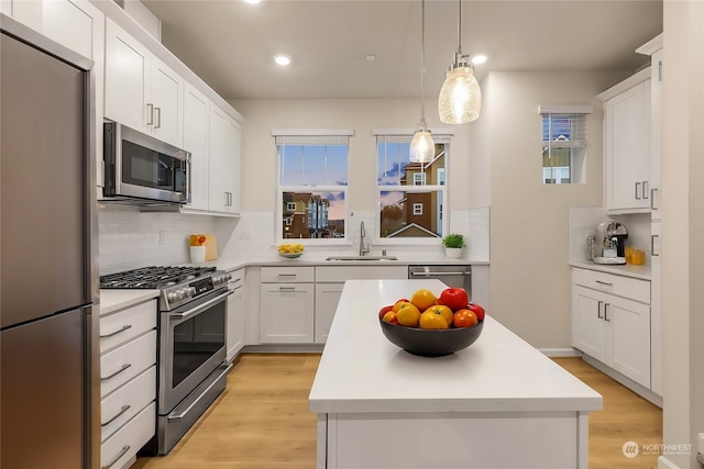 kitchen with sink, white cabinetry, hanging light fixtures, appliances with stainless steel finishes, and decorative backsplash