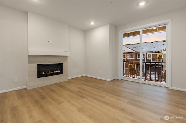 unfurnished living room featuring a tiled fireplace and light hardwood / wood-style floors