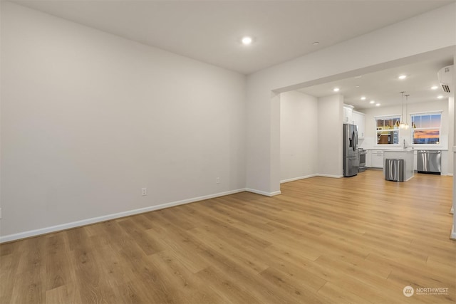 unfurnished living room featuring sink and light wood-type flooring