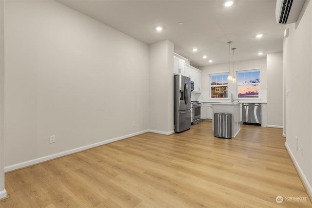 kitchen featuring appliances with stainless steel finishes, decorative light fixtures, white cabinetry, a center island, and a wall unit AC