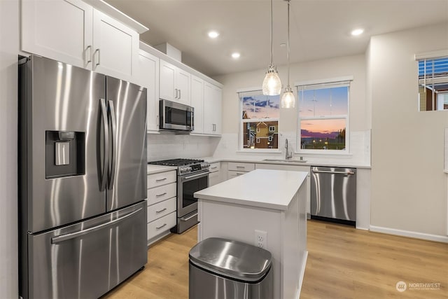 kitchen featuring white cabinetry, stainless steel appliances, sink, and a kitchen island