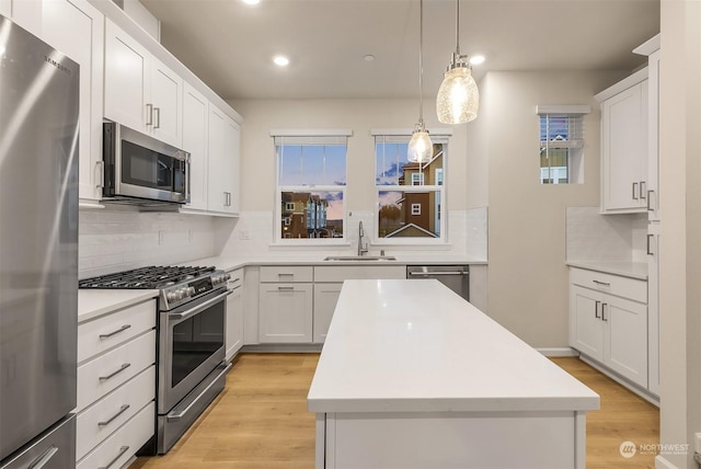 kitchen with sink, decorative light fixtures, a center island, appliances with stainless steel finishes, and white cabinets